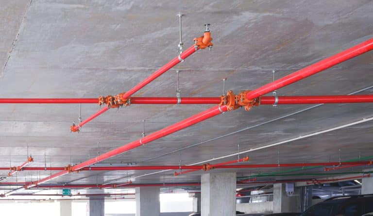 Red fire protection water pipeline system on ceiling inside of parking garage building